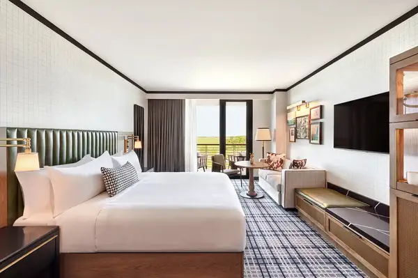 Luxurious hotel room with a bed, sitting area, and view of the balcony and outdoors