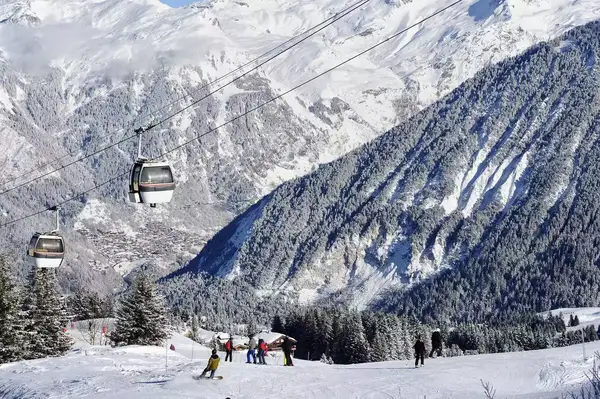 Skiers at Courchevel resort with gondola and mountains in background