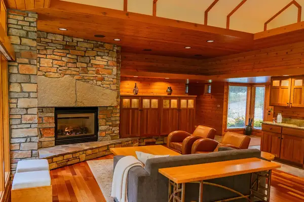A cozy living room with a fireplace stone accents wooden walls and comfortable seating