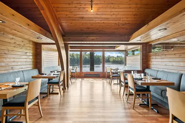 A dining area with wooden interiors large windows and tables set with plates