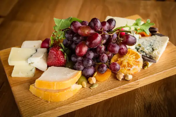 Fruit and cheese platter with grapes strawberries and cheese slices on a wooden board
