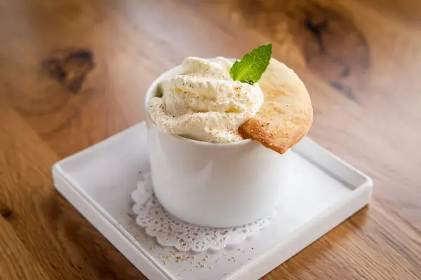Dessert with whipped topping mint garnish and thin pastry served in a white bowl