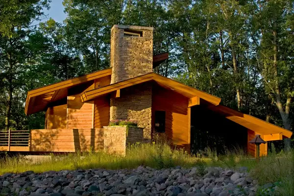 A house with wooden features and a chimney in a wooded area