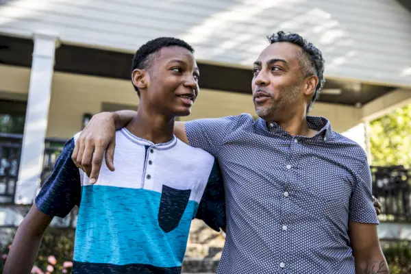 father and son talking in front of house