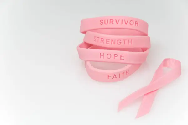 stack of pink rubber bracelets reading survivor, strength, hope, faith and pink ribbon next to it