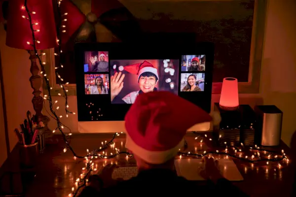 man in front of computer in video call with friends and relatives in christmas time