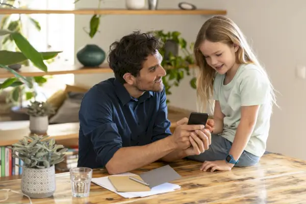 man showing smart phone to daughter while discussing at home