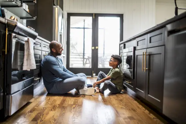 father talking with tween son in residential kitchen