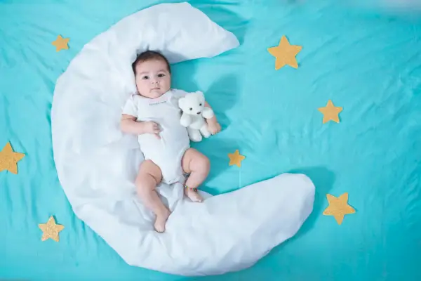 beautiful latin baby girl, two months old, lying on a white sheet in the shape of a moon with yellow stars to each side and a blue sheet underneath it all