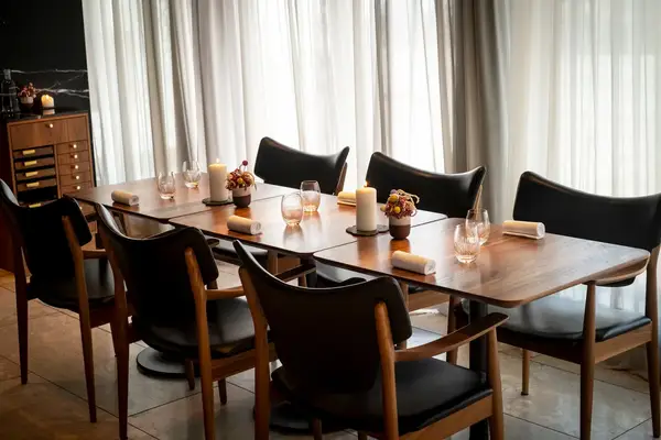 Dining table set for guests surrounded by chairs in a softly lit restaurant interior