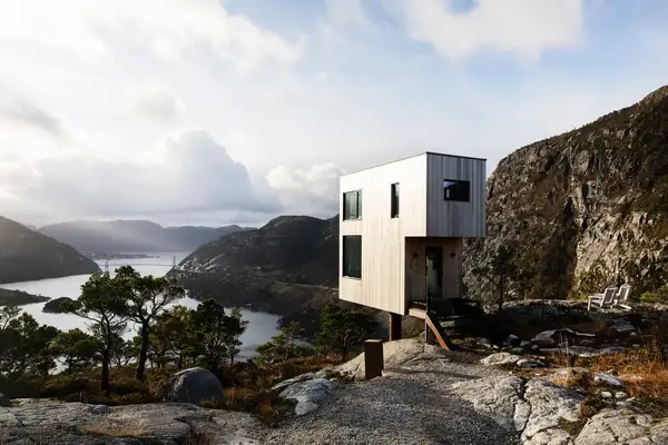 Modern wooden house on a rocky mountaintop overlooking a scenic fjord