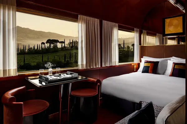Luxury train compartment with a bed table and panoramic window view of the countryside