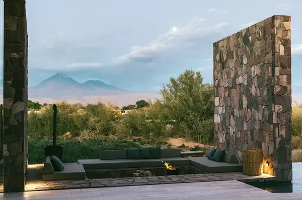 Outdoor seating area framed by stone walls with a natural landscape view including distant mountains