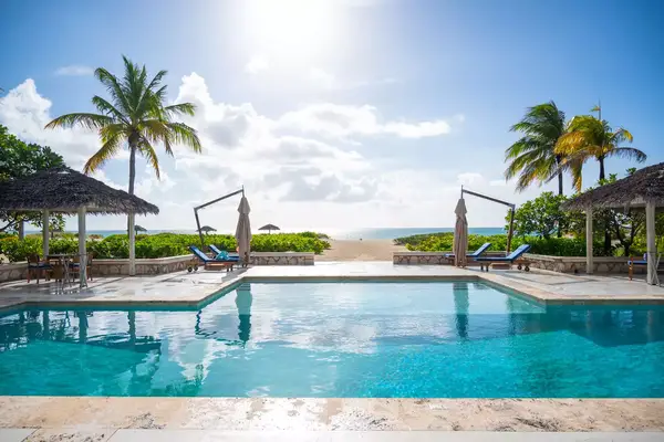 sunny day overlooking outdoor pool leading out to beach waterfront
