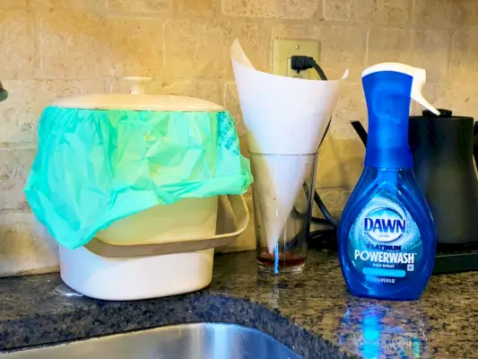 kitchen sink with dawn powerwash, a bamboo compost bin, and a homemade fruit fly trap consisting of a glass with vinegar in the bottom and a paper cone