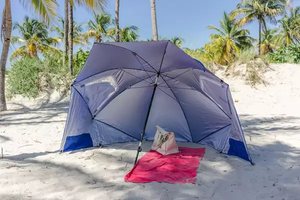 Sport-brella Premiere UPF 50+ Umbrella set up on a beach with a towel and bag under it
