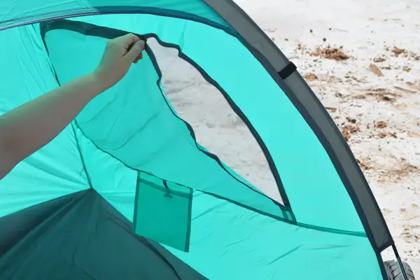 Closeup of a person zipping one of the windows of the WhiteFang 3-Person Beach Tent