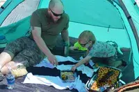 Adult and child eating inside of the WhiteFang 3-Person Beach Tent