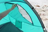 Closeup of a person zipping one of the windows of the WhiteFang 3-Person Beach Tent