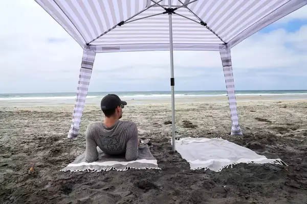 A person lays on a towel under the CoolCabanas CoolCabana 5