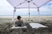 A person lays on a towel under the CoolCabanas CoolCabana 5