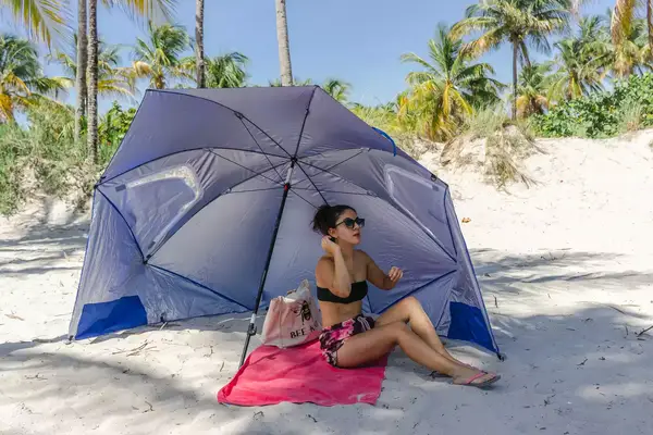 A person pulling the OutdoorMaster Beach Umbrella out of it
