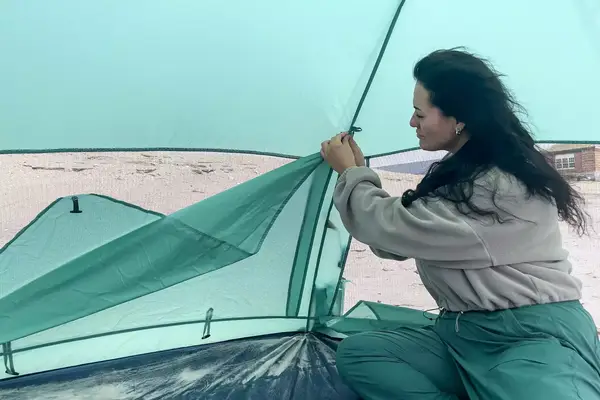 A person secures a side of the Kelty Cabana Shelter