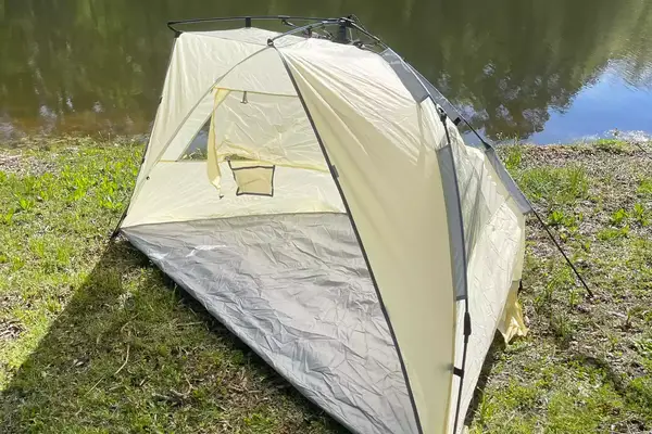 Oileus XL Beach Tent displayed on grass near a pond 
