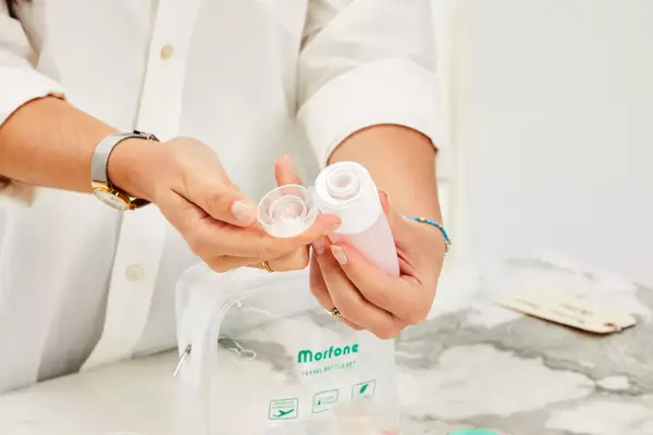 Person lifting cap off of Morfone 16 Pack Travel Bottle