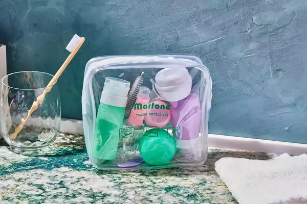 Morfone 16 Pack Travel Bottles displayed on marble counter next to cup with toothbrush