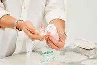 Person lifting cap off of Morfone 16 Pack Travel Bottle