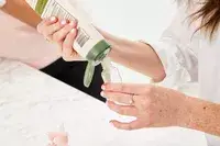 Person filling a Vitog Travel Bottle with product