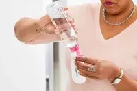 Person dispensing product into Liquisnugs Premium Leak-Proof Silicone Travel Bottles