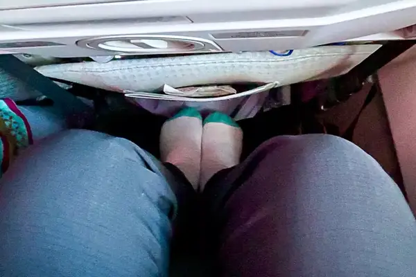 A person using the Beskar Airplane Foot Rest on an airplane