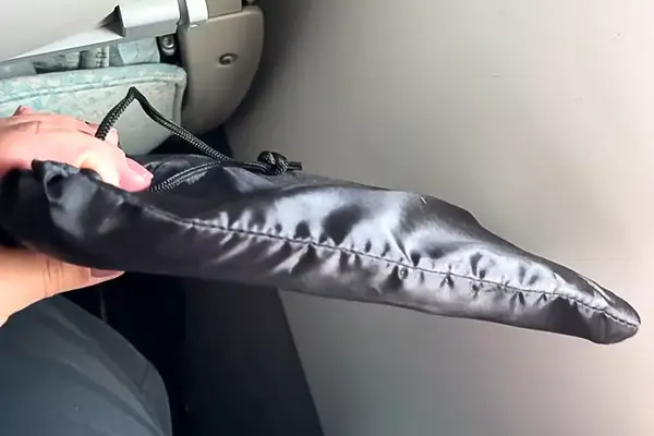 A person holding the Beskar Airplane Foot Rest in the carry bag