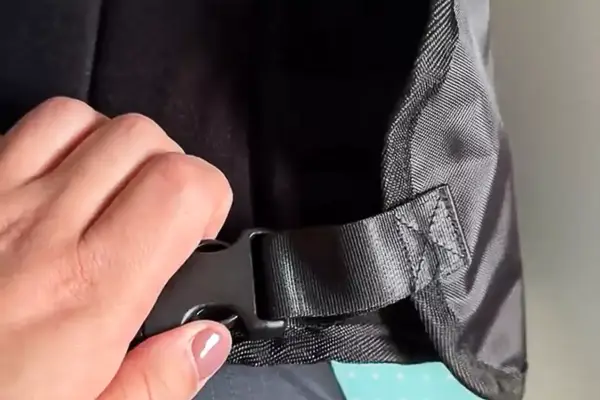 A person unclasping the buckle on the Beskar Airplane Foot Rest