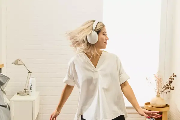 A person dancing in a bedroom setting while wearing the Sonos Ace Headphones