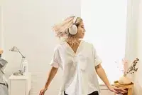 A person dancing in a bedroom setting while wearing the Sonos Ace Headphones