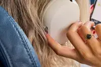 A close-up of a finger pressing a button on the Sonos Ace Headphones while a person wears them