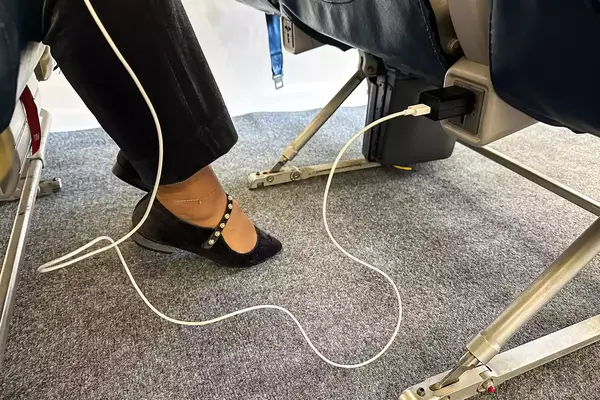 Tumaber 3-Pack Apple 10-foot Lightning to USB Cords plugged into an airplane seat