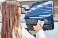 Person stowing the Away The Carry-On in the overhead compartment on an airplane