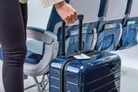 Hand holding handle of Away The Carry-On in plane aisle 