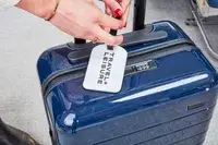 Hand attaching luggage tag to Away The Carry-On