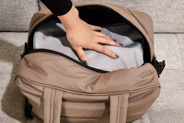 A hand pressing an item into the Calpak Luka Duffel Bag