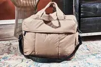 The Calpak Luka Duffel Bag on a floor next to couch and end table