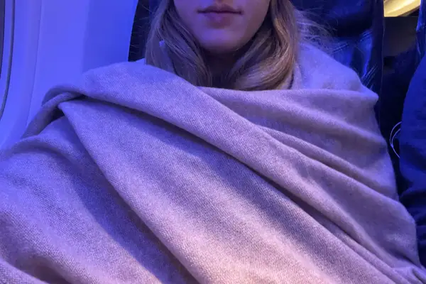 Person wrapped in the White+Warren Cashmere Travel Wrap on an airplane