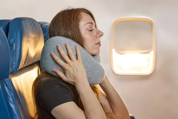 A person holding the Ostrich Pillow Go Neck Pillow on their neck
