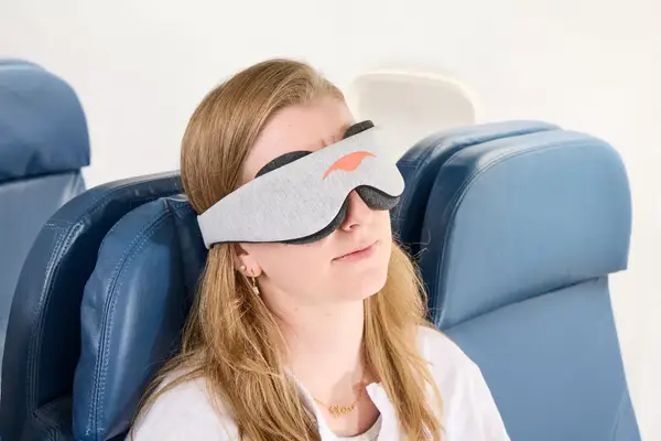 A person wearing the Manta Sleep Mask on a plane