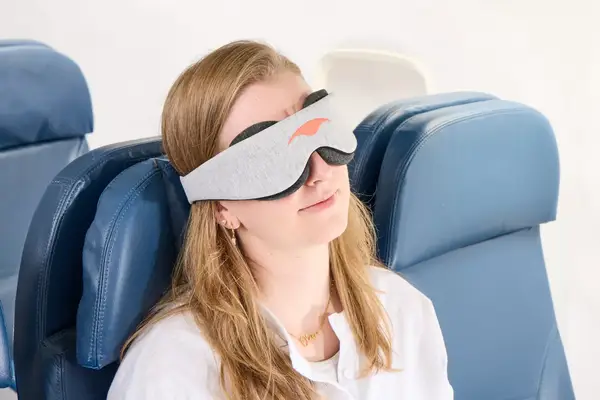 A person wearing the Manta Sleep Mask on an airplane