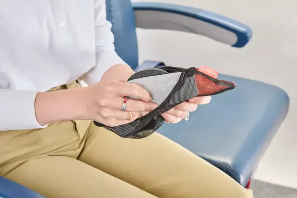 A person removing the Manta Sleep Mask from a travel pouch